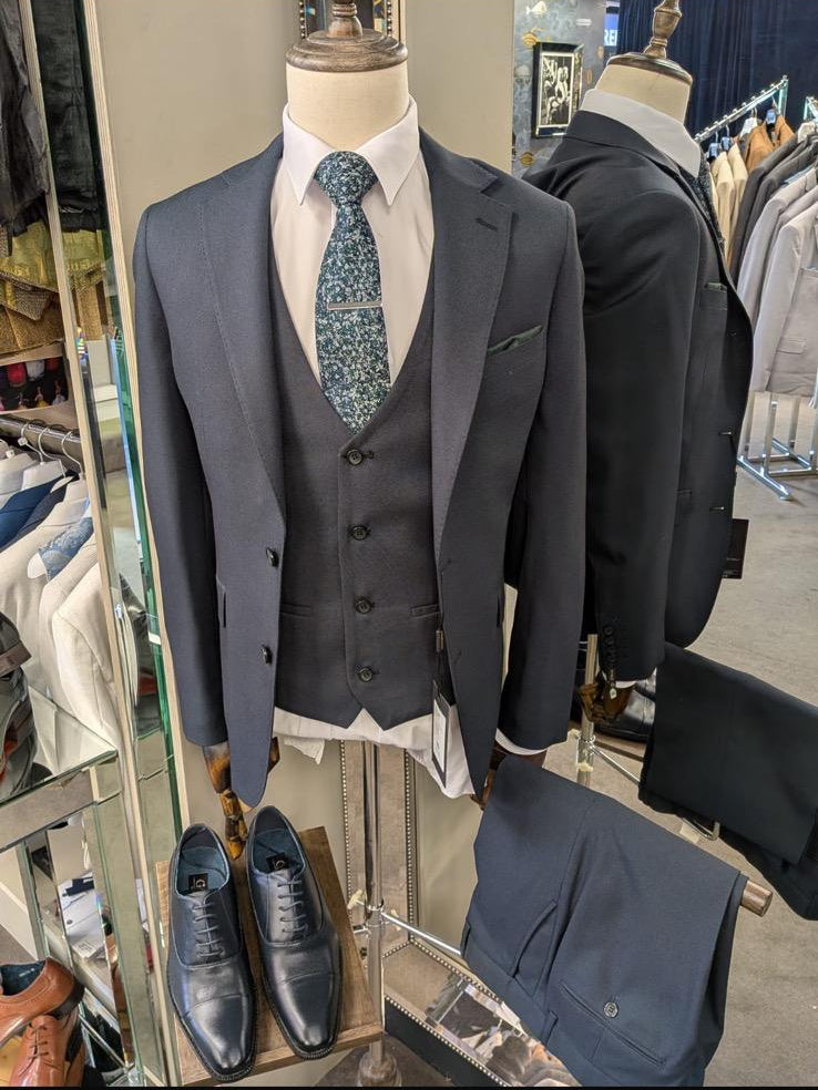 Mannequin wearing a gray suit with a tie and shoes in a store setting