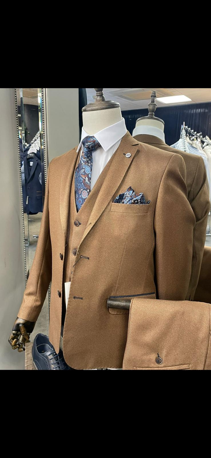 Brown suit on a mannequin with a patterned tie and pocket square in a store setting.